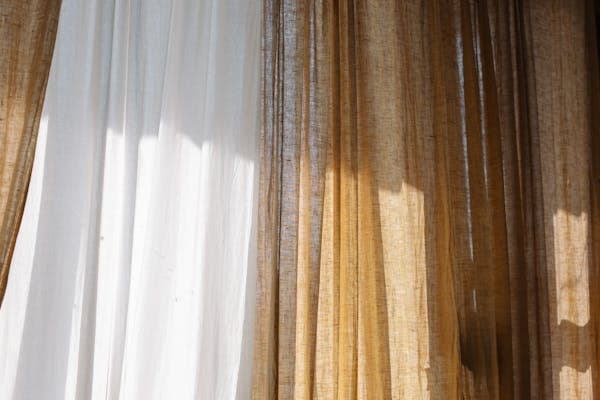 Warm sunlight streaming through linen curtains at Aurelia — photo by cottonbro studio on Pexels